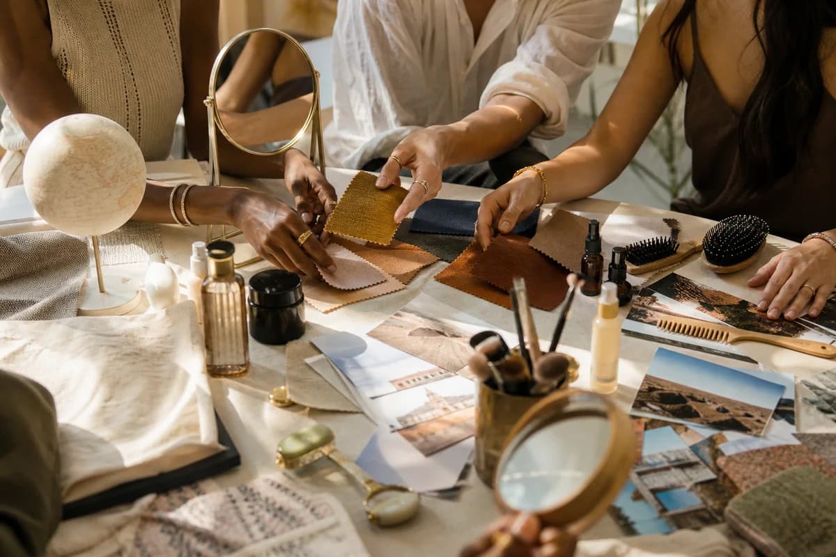 Diverse hands arranging beauty, grooming, mirror, and style items on a sunlit table